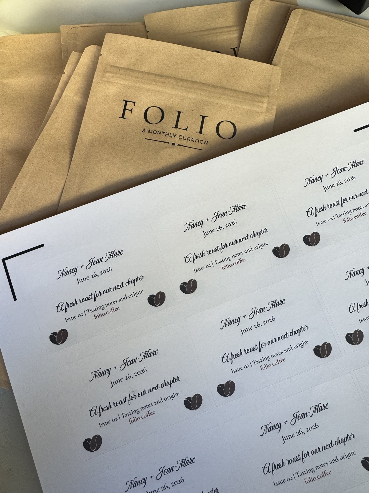 Wedding favor stickers laid out on a sheet, with stamped Folio bags in the background.